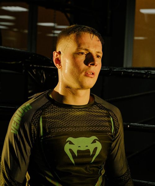 Man performing a strength exercise in a dark gym with cyan highlights.